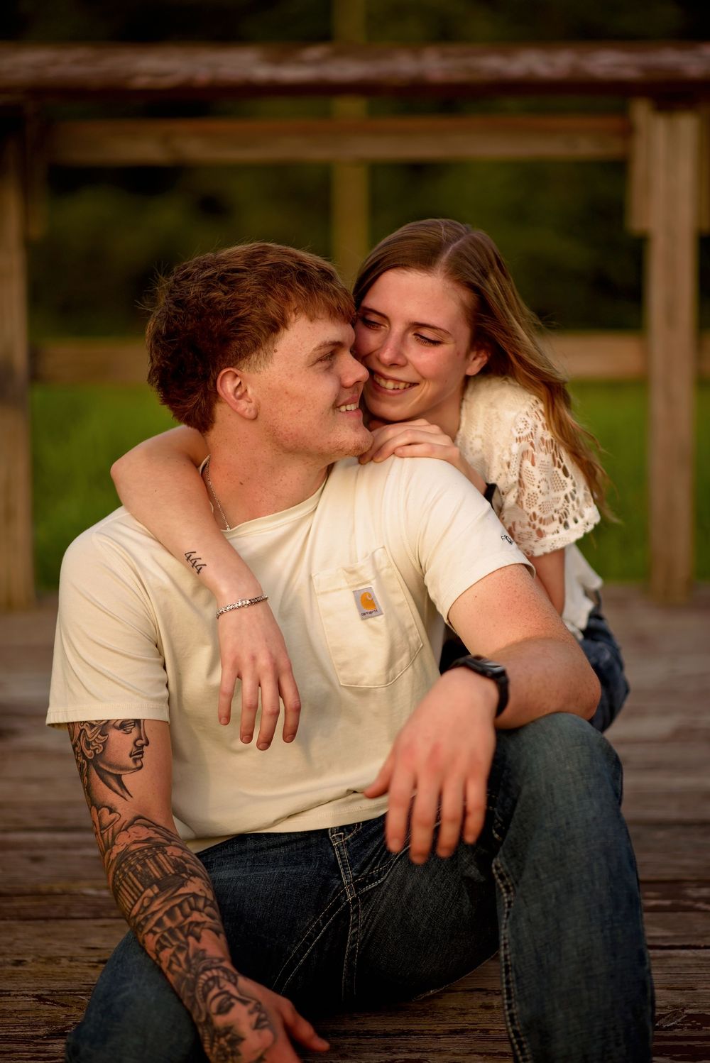 Couple sharing an intimate moment while sitting on wooden decking at sunset.