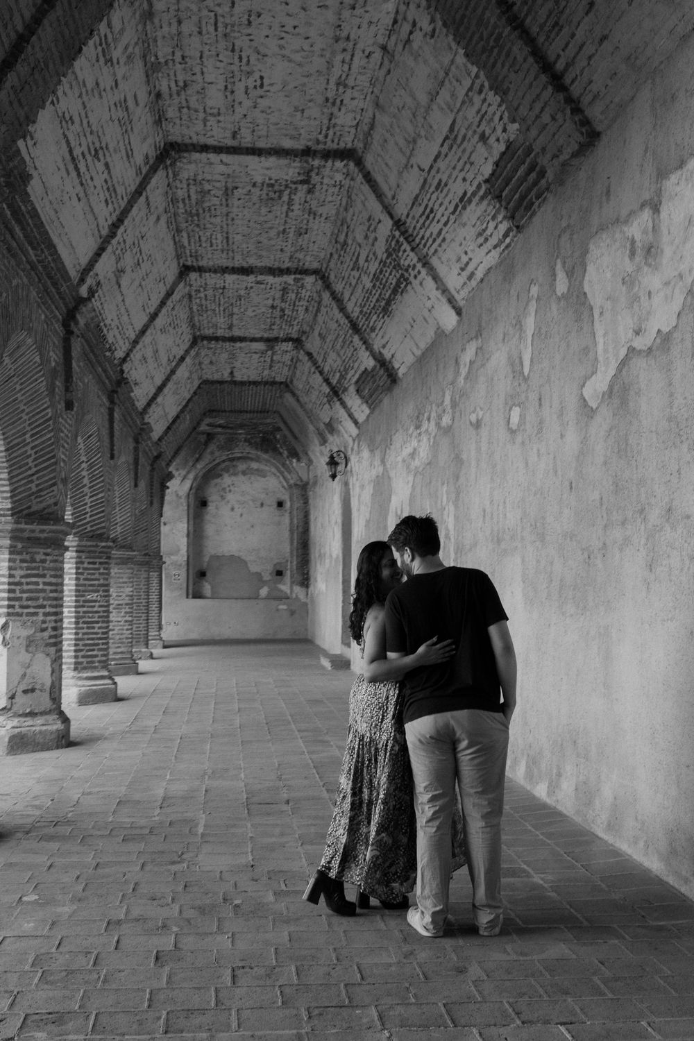 A series of black and white images showing silhouettes in an arched brick corridor, creating a sequential narrative effect.
