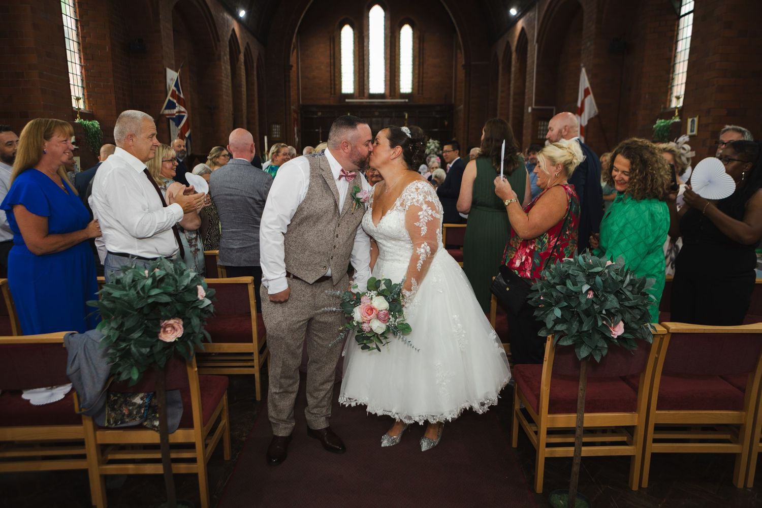 Special moment during a church ceremony as attendees gather together under ornate stained glass windows.