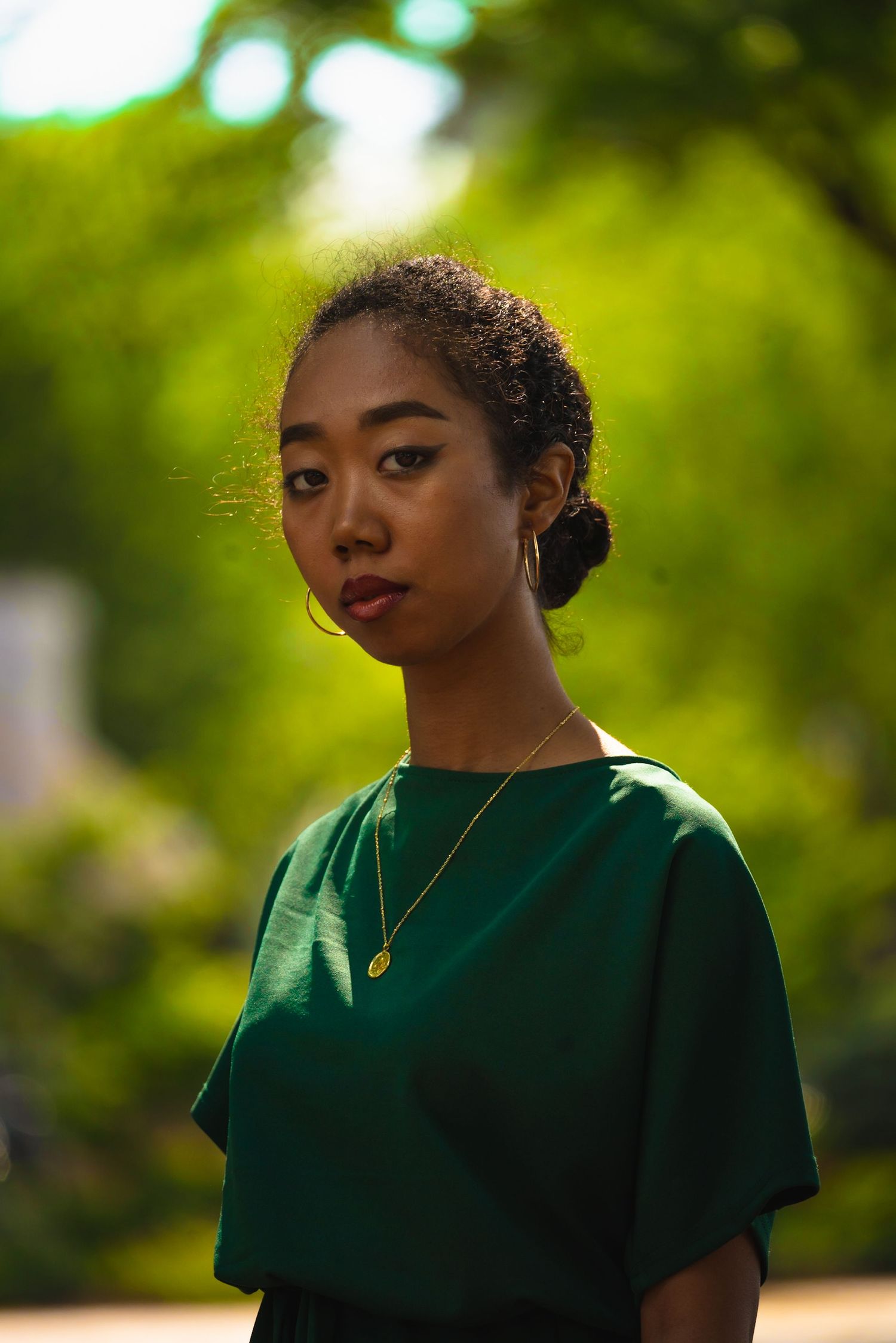 Portrait series in emerald green dress against natural outdoor backdrop.