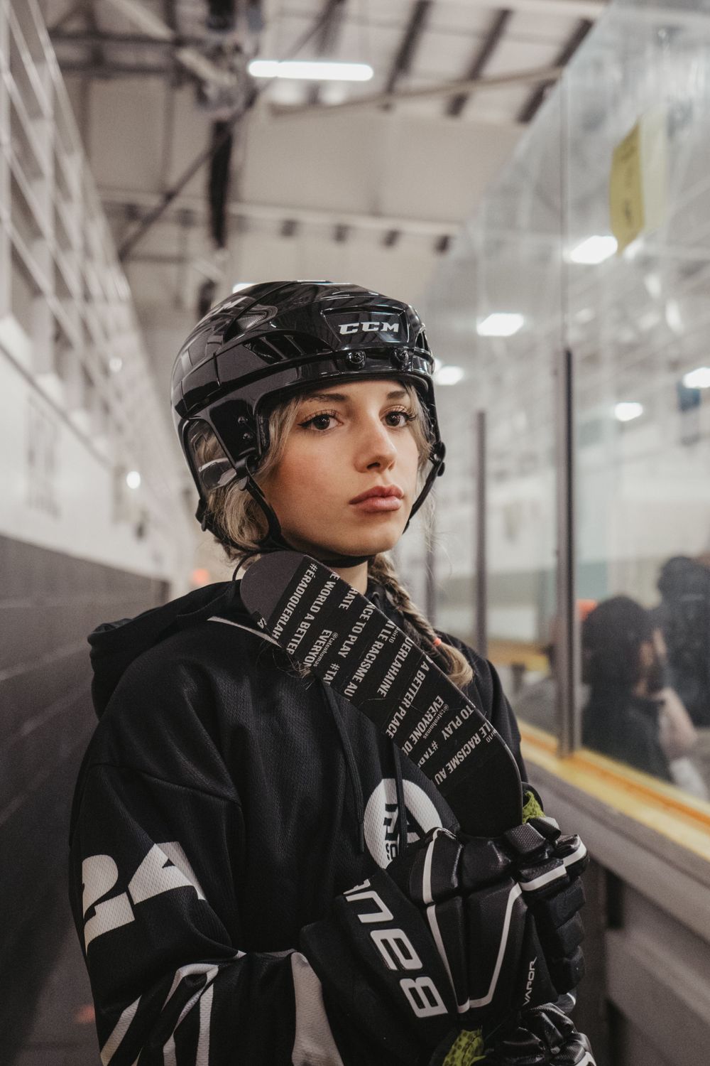 Hockey player in protective gear stands in indoor rink hallway.