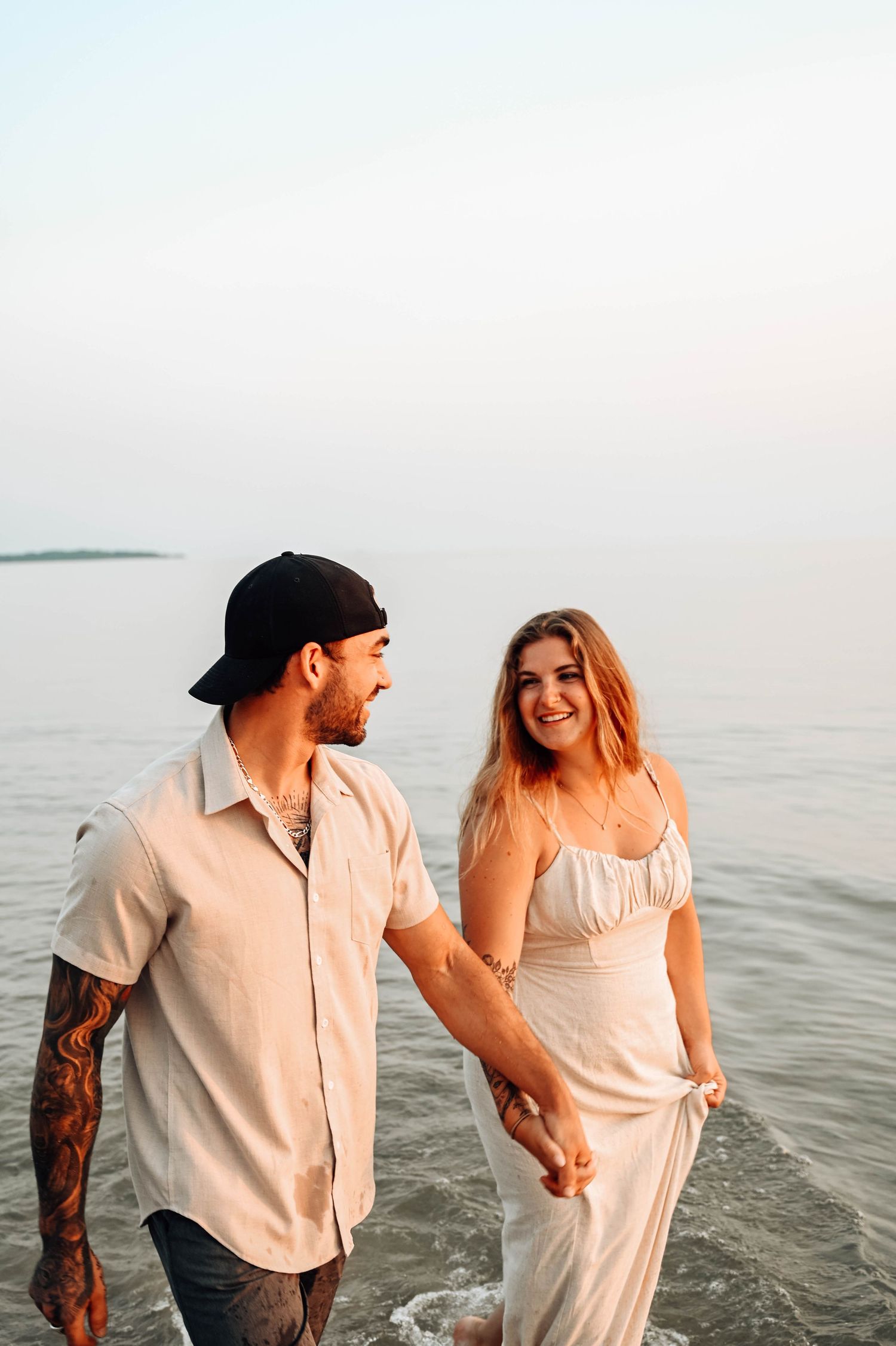 Couple walking and laughing together at the beach during sunset.
