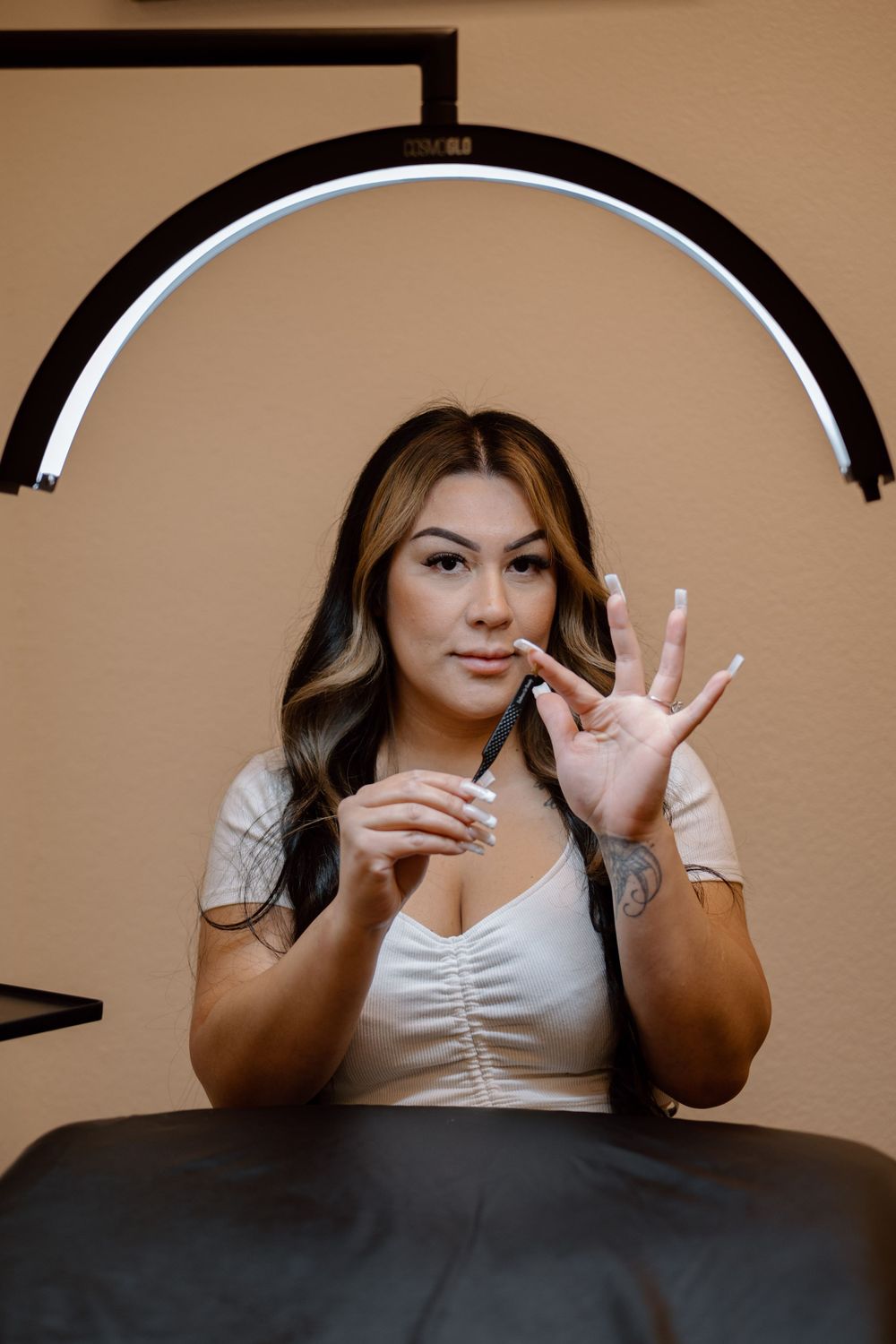 Beauty professional in white top showing lash extension services in a salon setting.