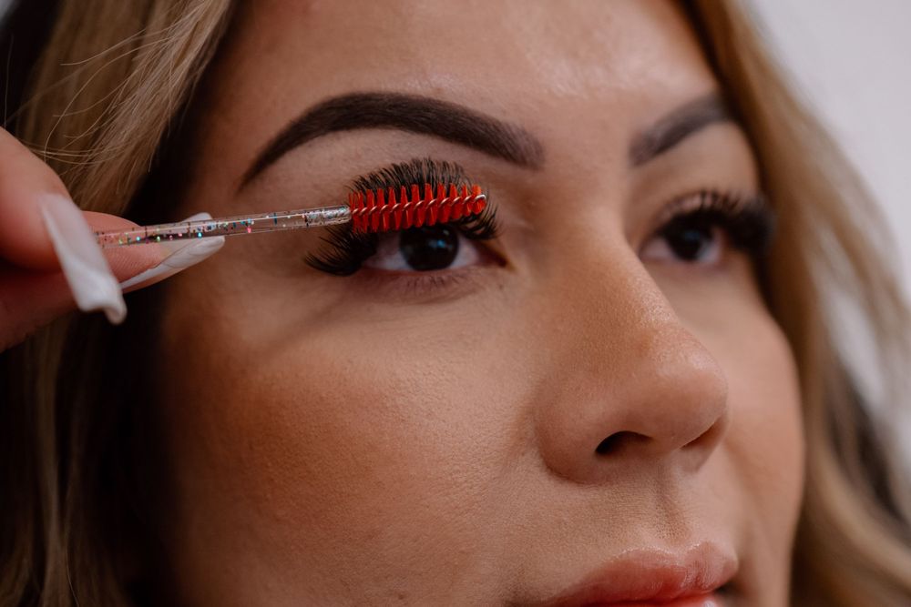 Close-up shot of an eyelash grooming procedure with a red brush.