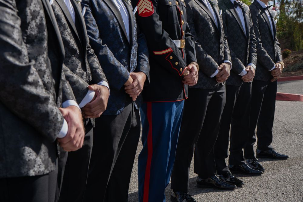 Row of formally dressed guests standing at attention during wedding ceremony.