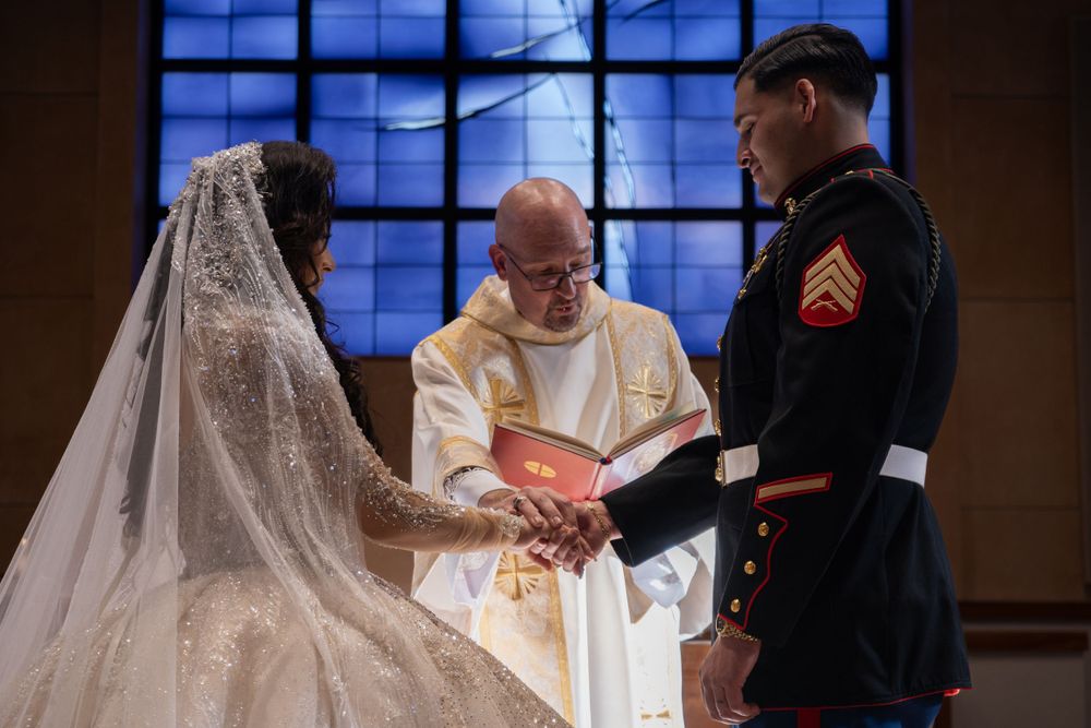 Priest performing marriage ceremony for couple in military uniform and white gown.