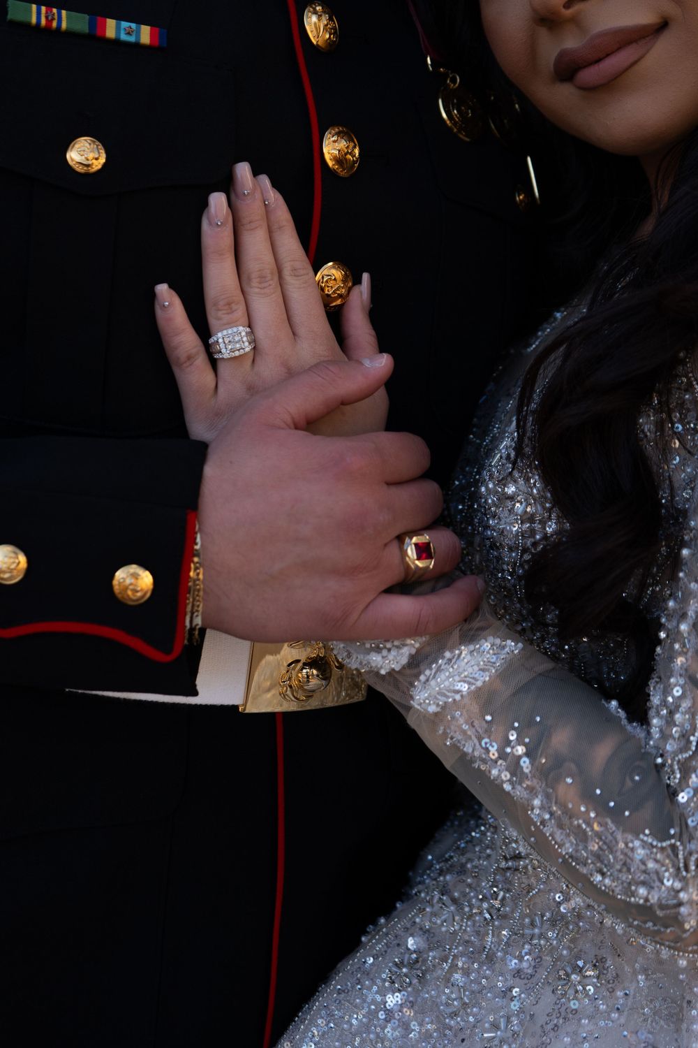 Close-up of sparkling engagement ring and military dress uniform details.