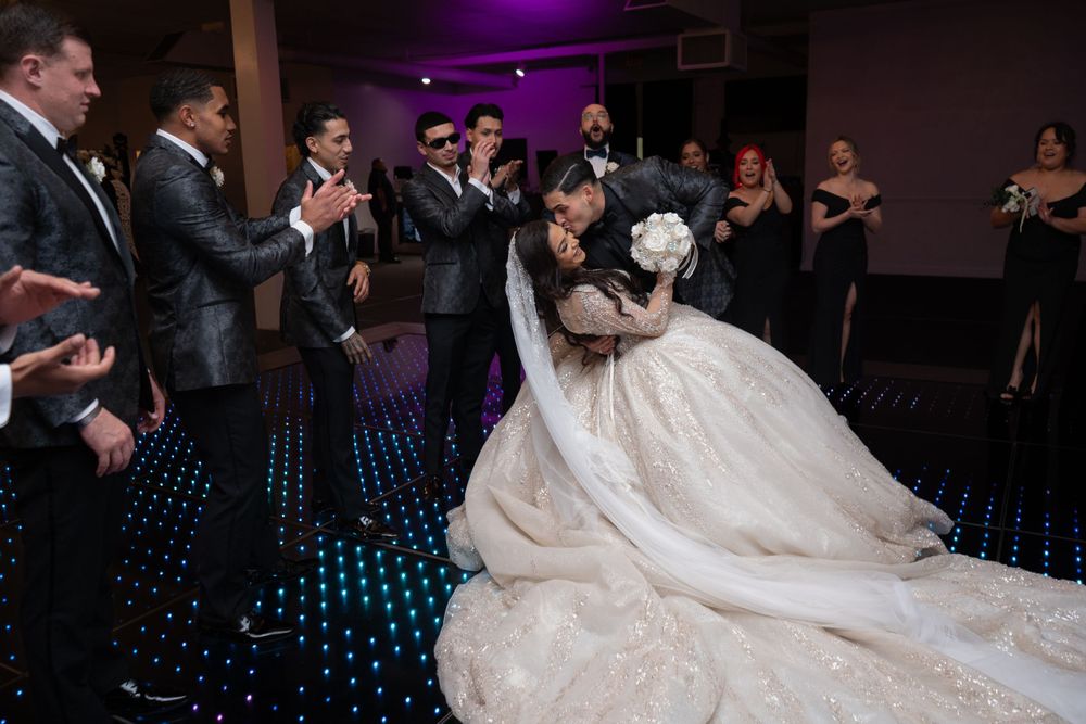 Wedding reception first dance on illuminated floor surrounded by guests.