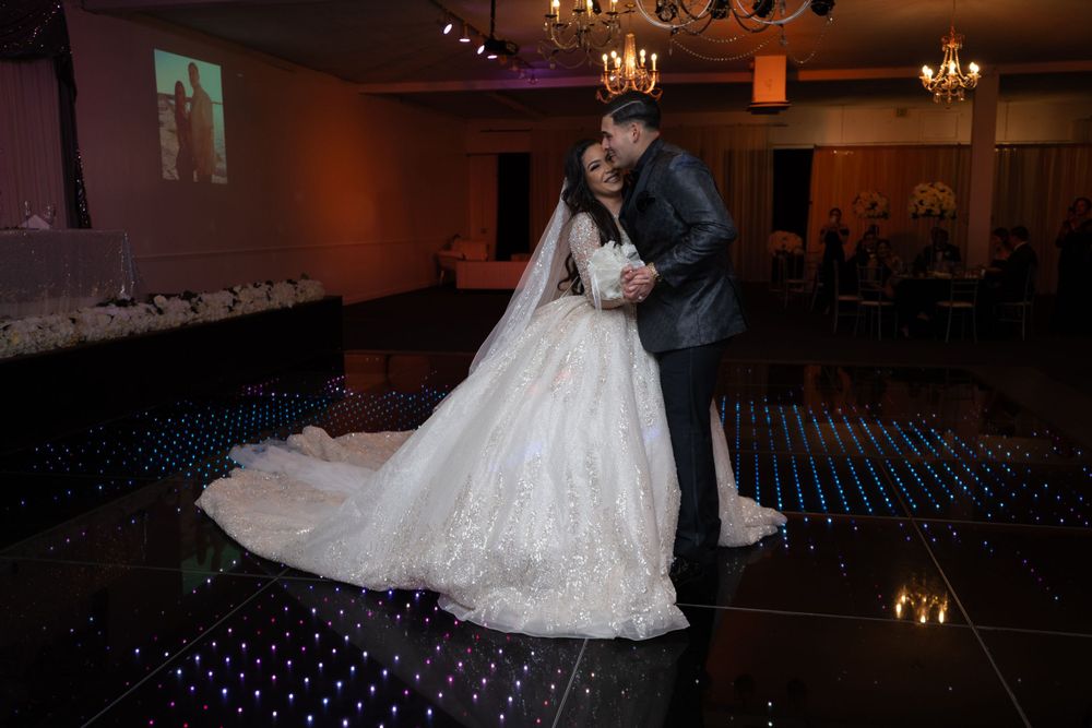 Romantic dance moment on LED-lit reception floor with bride's lace gown trailing.