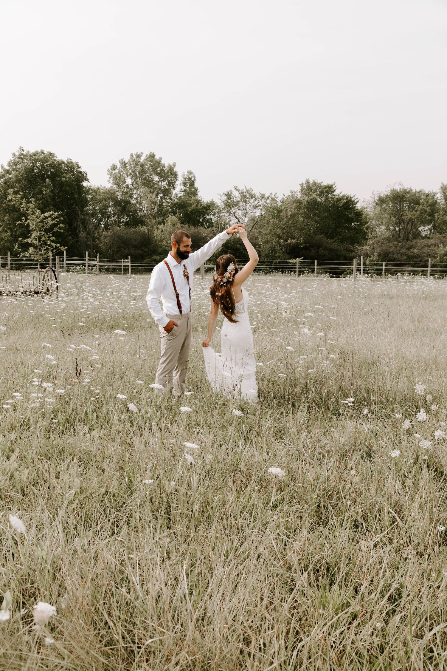 A couple dances in a dreamy meadow filled with wildflowers during their countryside wedding.
