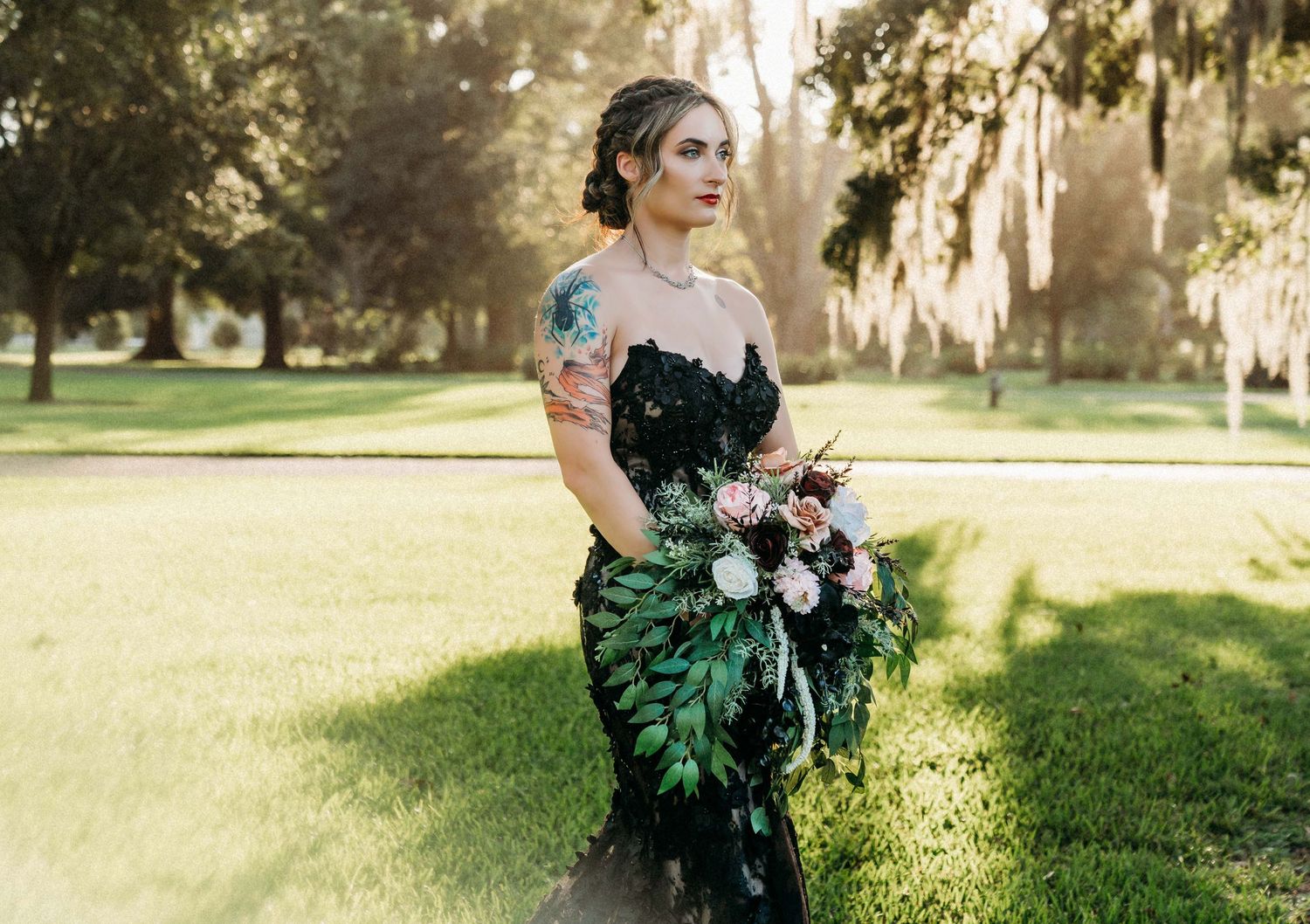 Elegant dress in dark emerald green with delicate lace detailing and a dramatic bouquet in a sunlit garden setting.