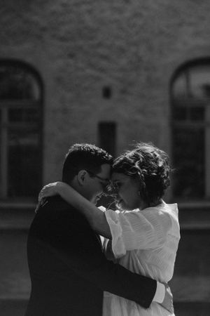 Hääpari seisoo vastakkain pihapiirissä ja halaa toisiaan.