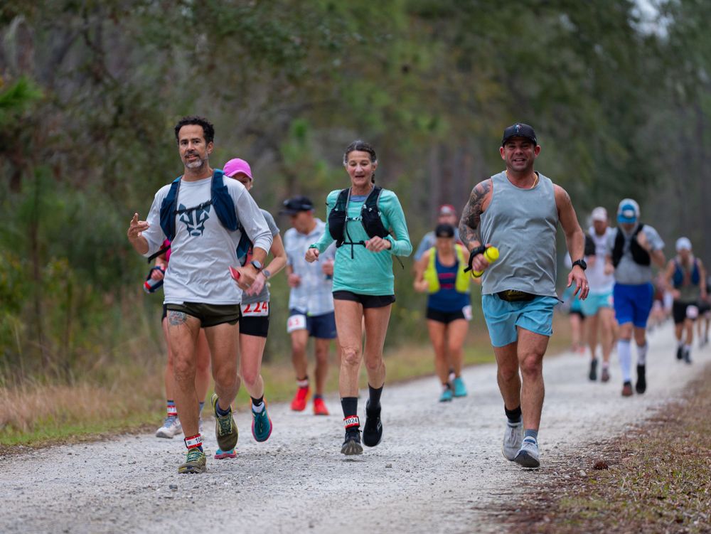 Participants running on a gravel trail during an endurance race through natural surroundings.