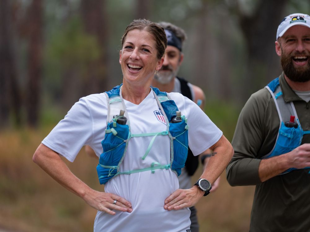 Runners in hydration packs share a joyful moment during a trail race.