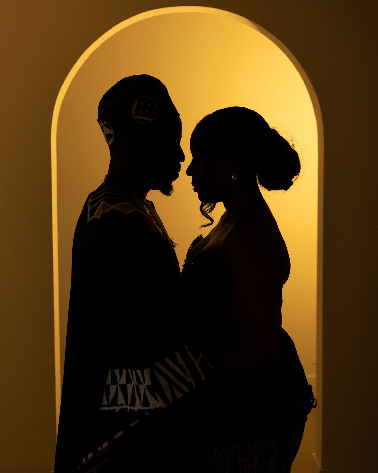 Silhouette of a couple in front of a golden archway with warm backlighting.