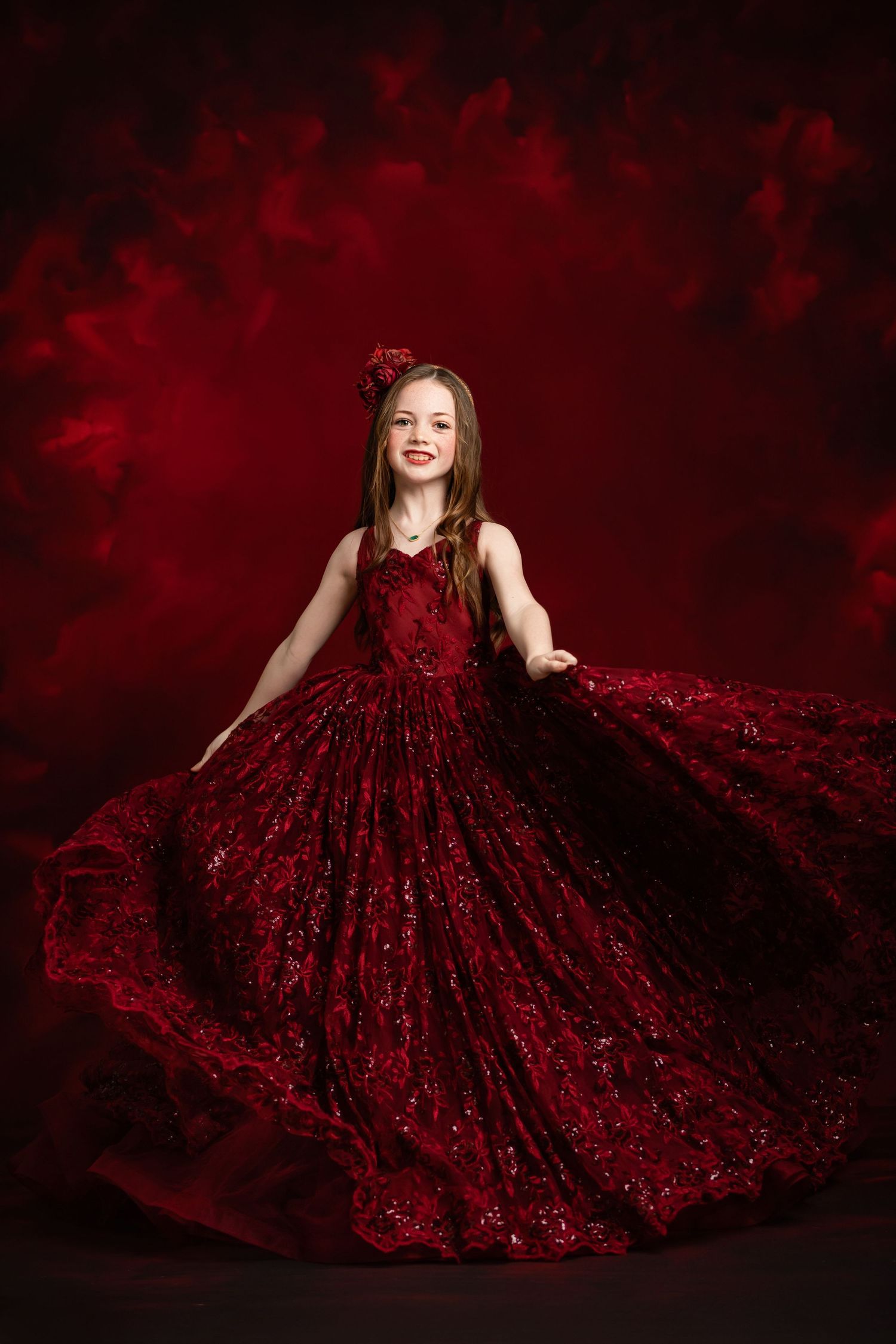 A luxurious burgundy sequined ballgown photographed against a warm brown textured backdrop.
