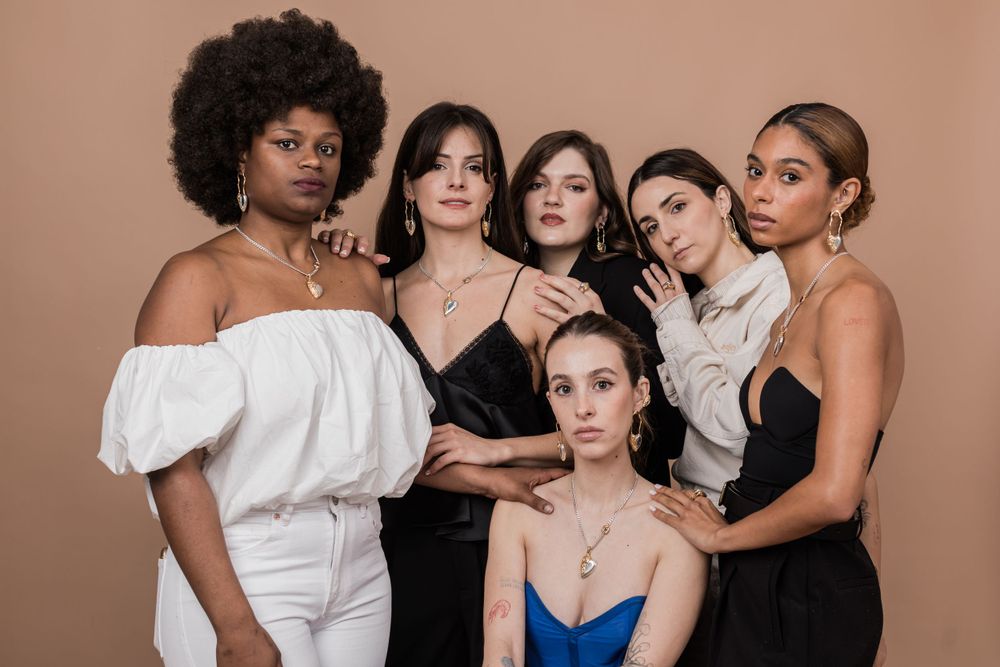 A diverse group of fashionable people pose together in elegant black and white outfits with one wearing blue.
