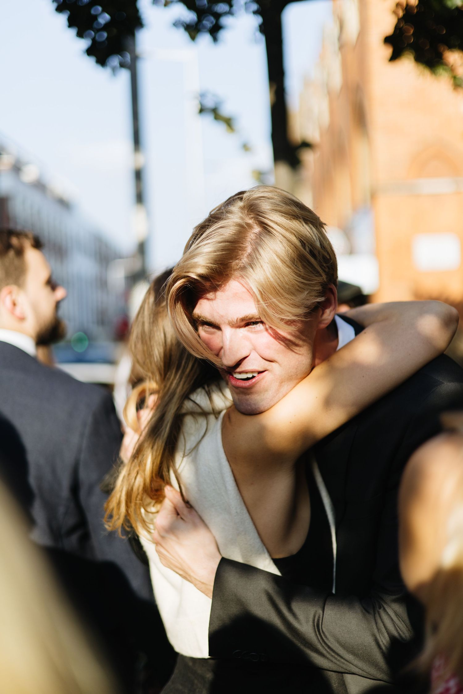 A joyful embrace captured in natural sunlight at an outdoor celebration.