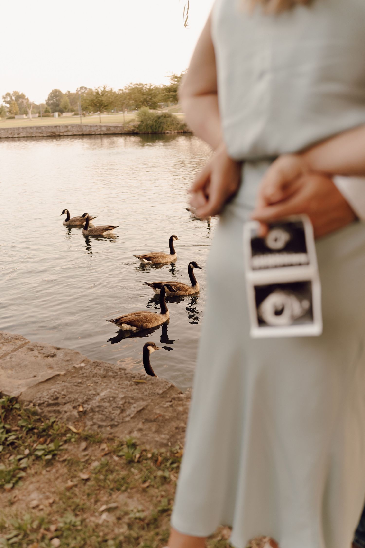 Elegant maternity portrait of a woman with a glowing smile, standing in a scenic outdoor location.