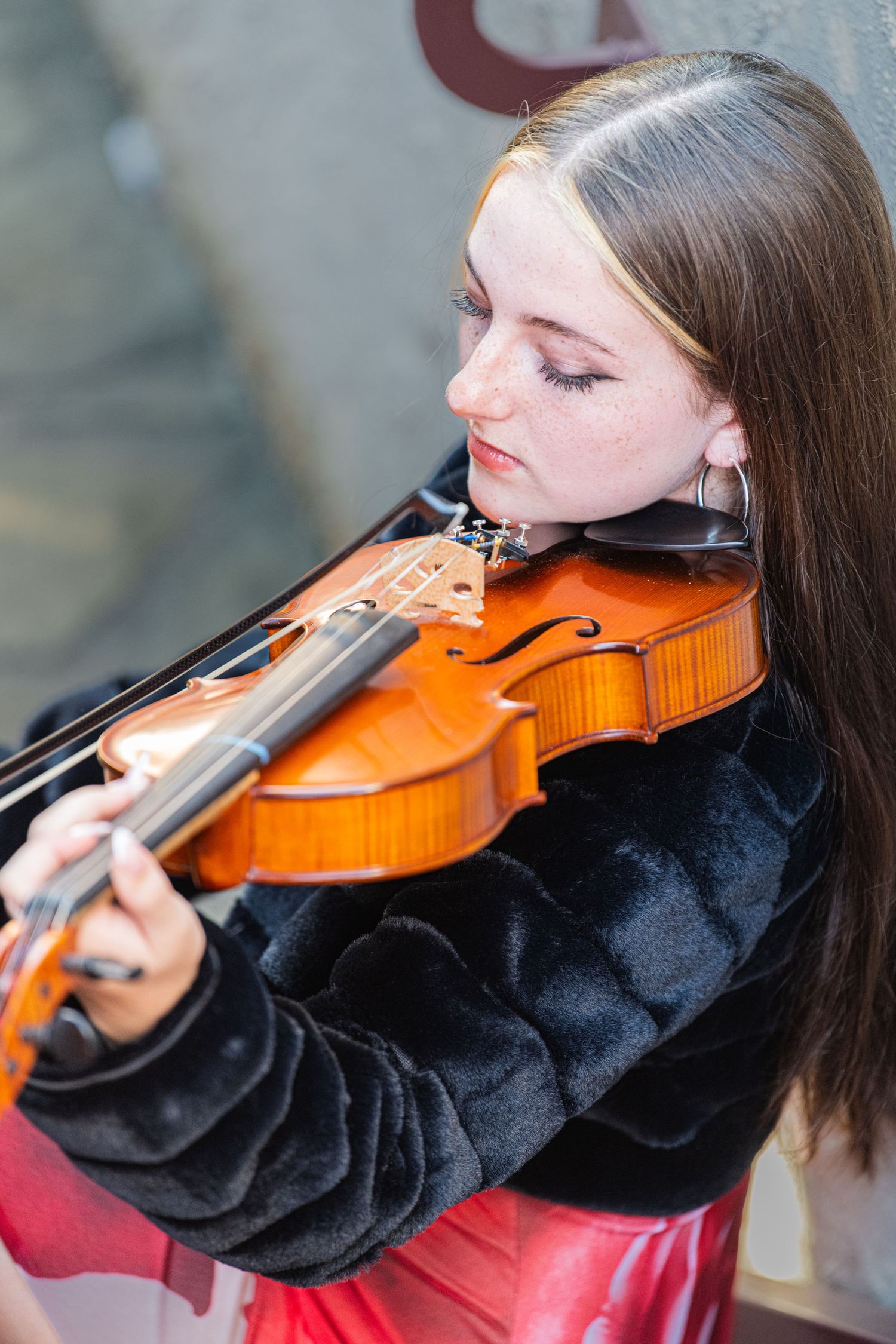 A senior girl playing the violin in the industrial setting of Revolution Mills, blending music with the historic charm of textile buildings