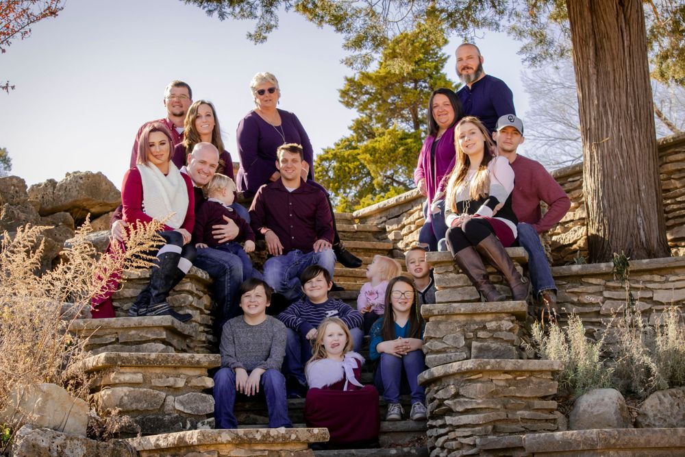 A cheerful family poses, sitting on textured stone steps and wall, showcasing their bond and happiness in a warm portrait.