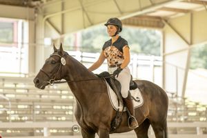 Riders train their horses at an indoor equestrian arena during a riding lesson or practice session.