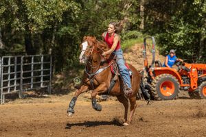 A rider guides their horse through a barrel racing pattern during a western rodeo competition.