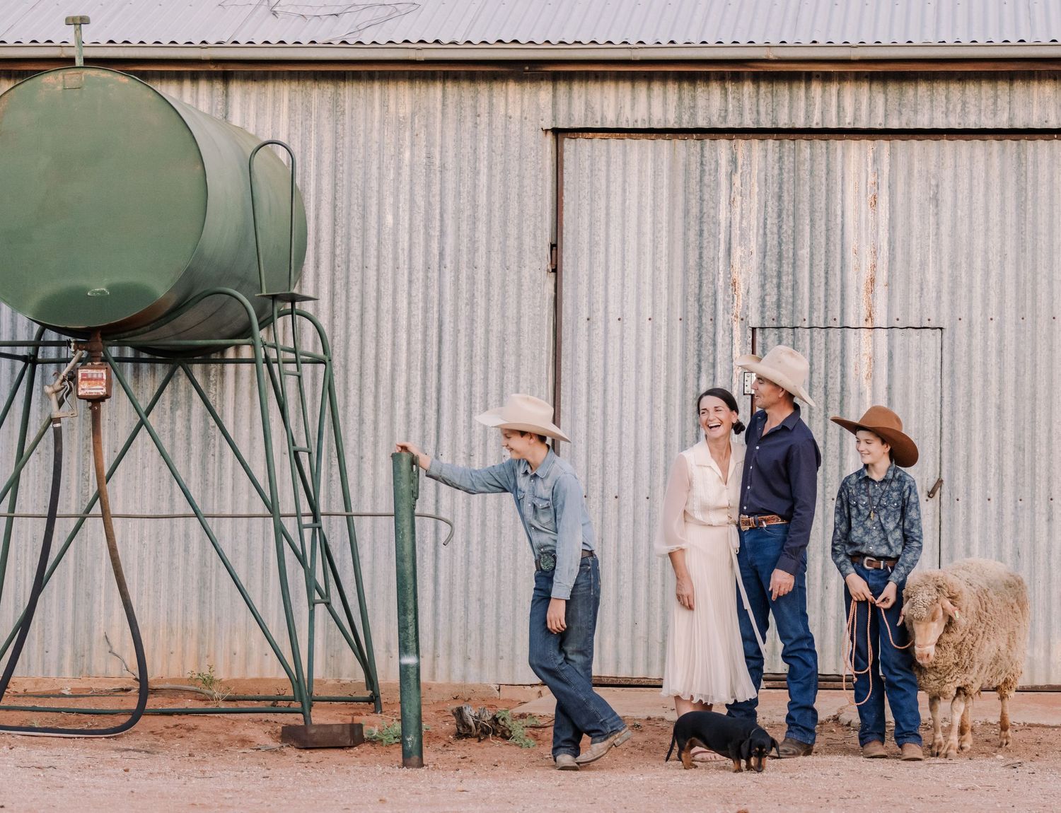 A rustic farm scene with water tank and corrugated metal wall in the background.