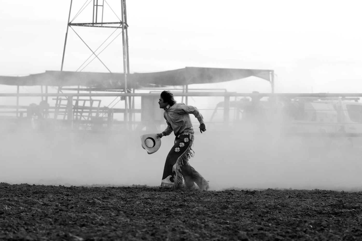 Silhouette of rodeo participant running through dusty arena.