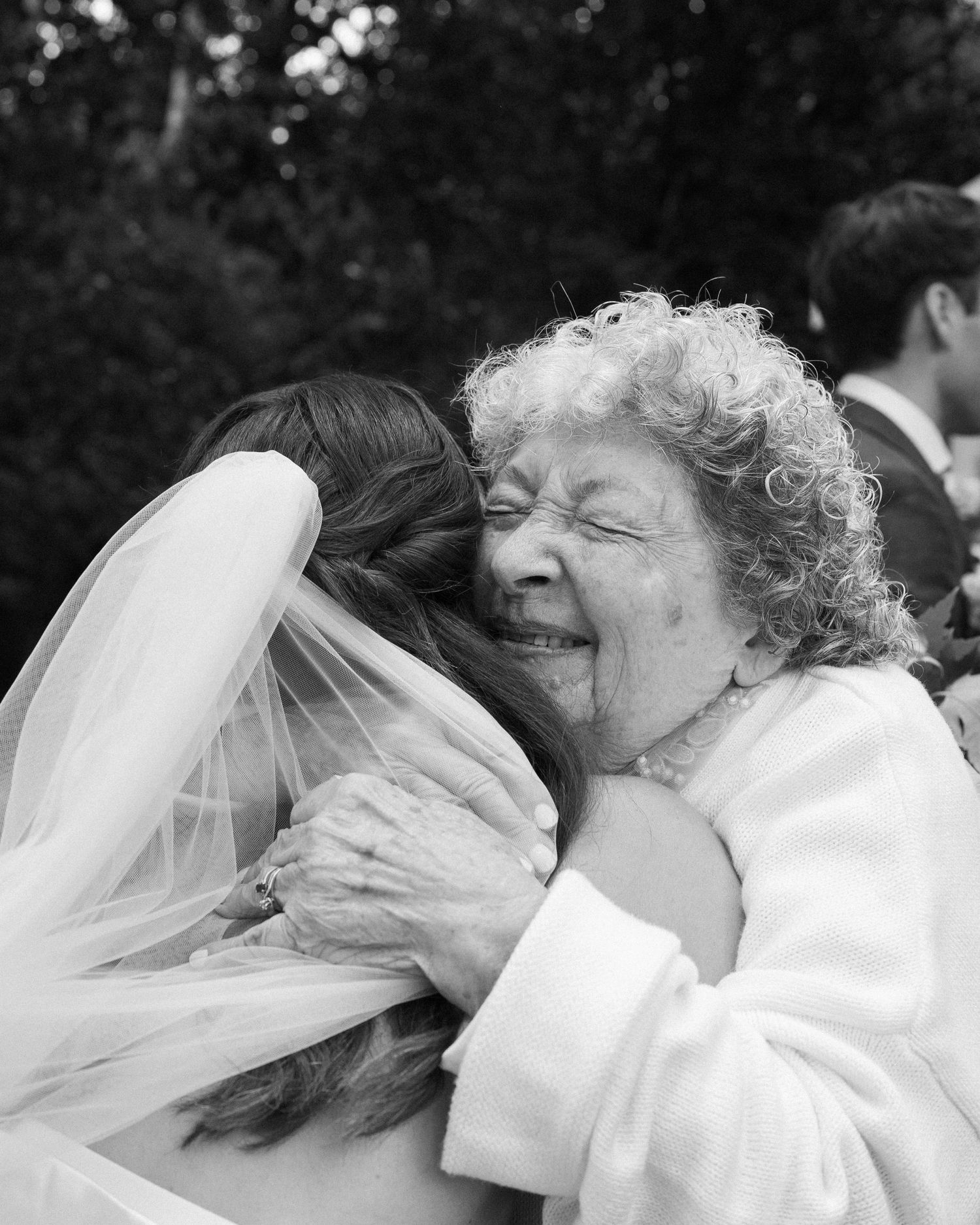 Tender moment shared between bride and elderly relative in black and white photograph.