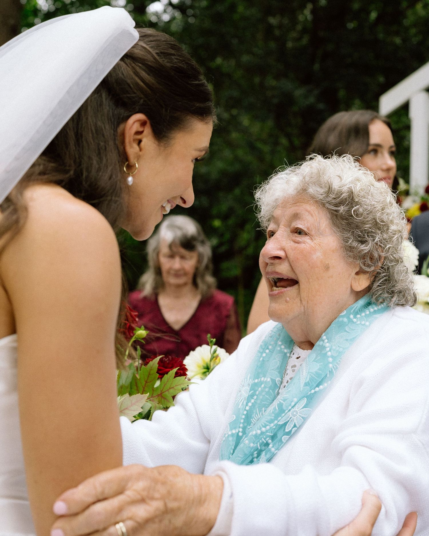 Joyful interaction between bride and elderly guest at wedding reception.