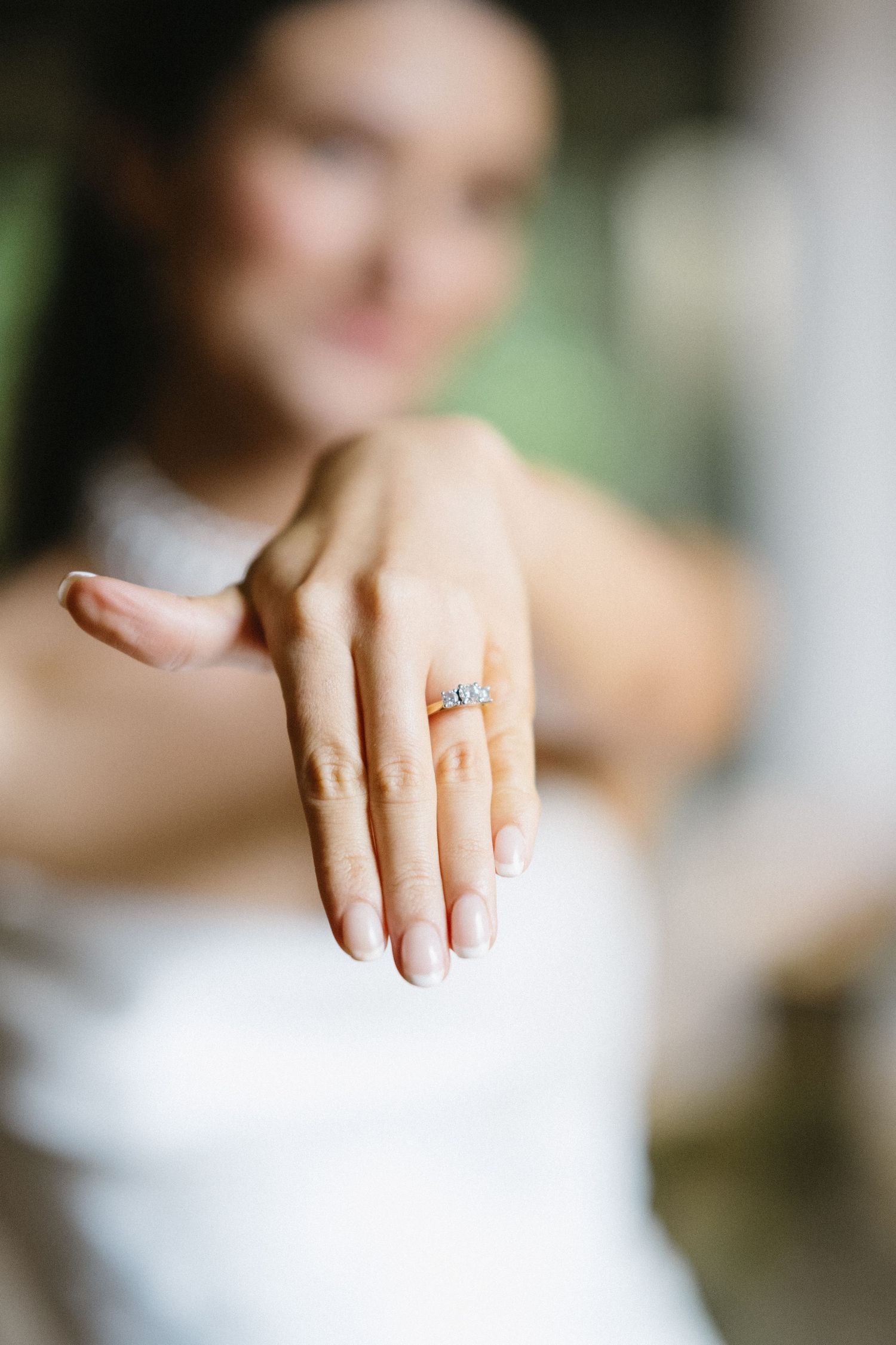 Close-up of engagement ring on bride's hand with soft focus background.