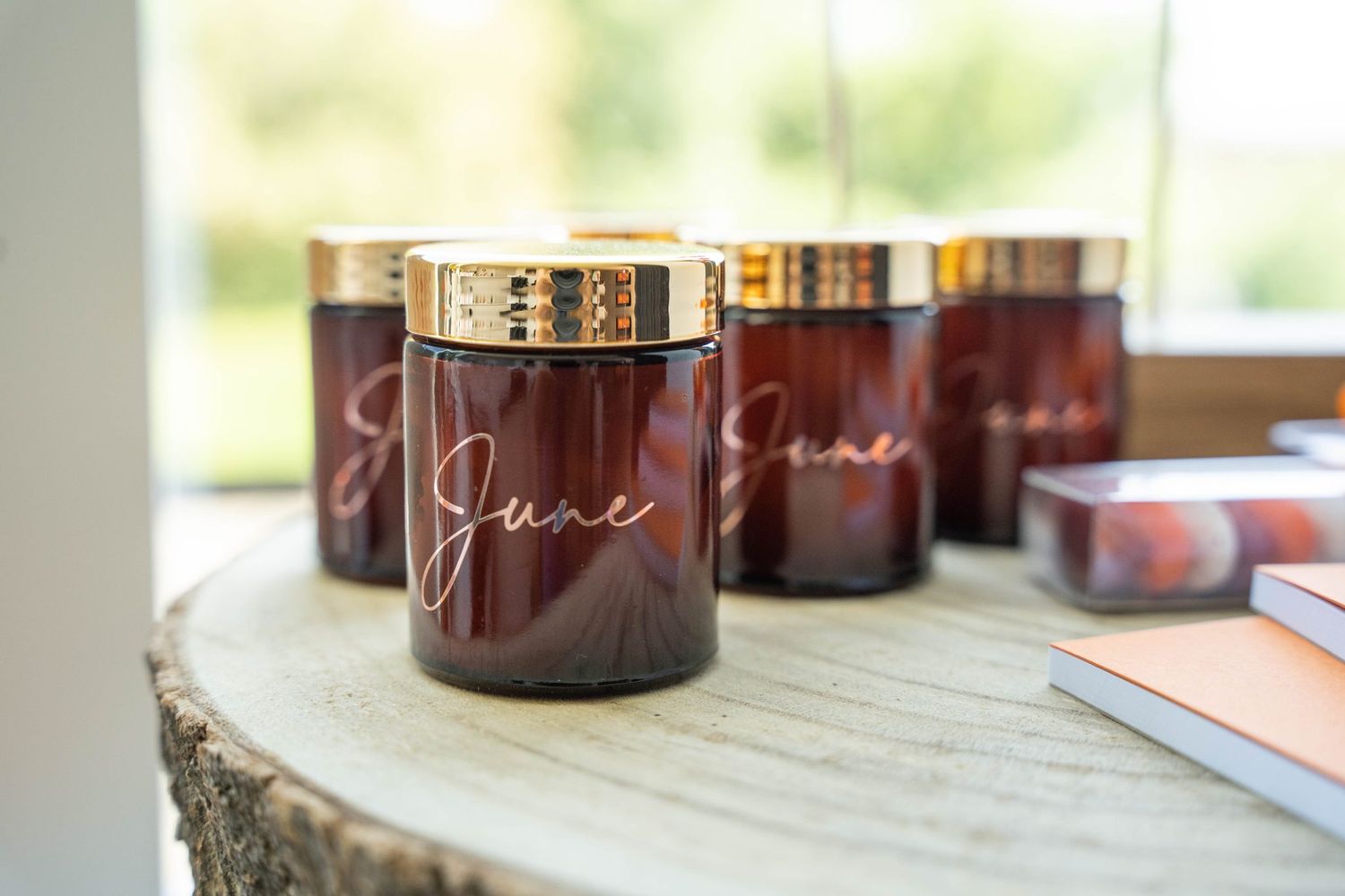 Amber glass candle jars with gold lids arranged on a wooden surface in natural lighting.