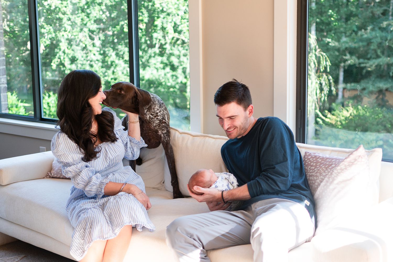 A family with their newborn include their pet in their newborn session at home.