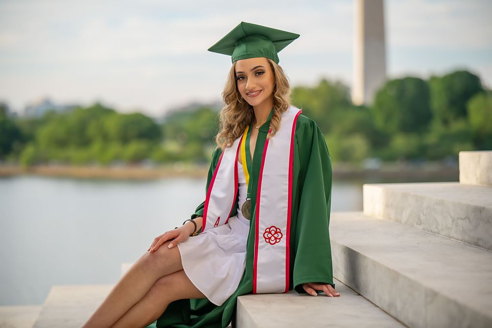 Graduation photoshoot at the Jefferson Memorial featuring green cap and gown with decorative sashes.