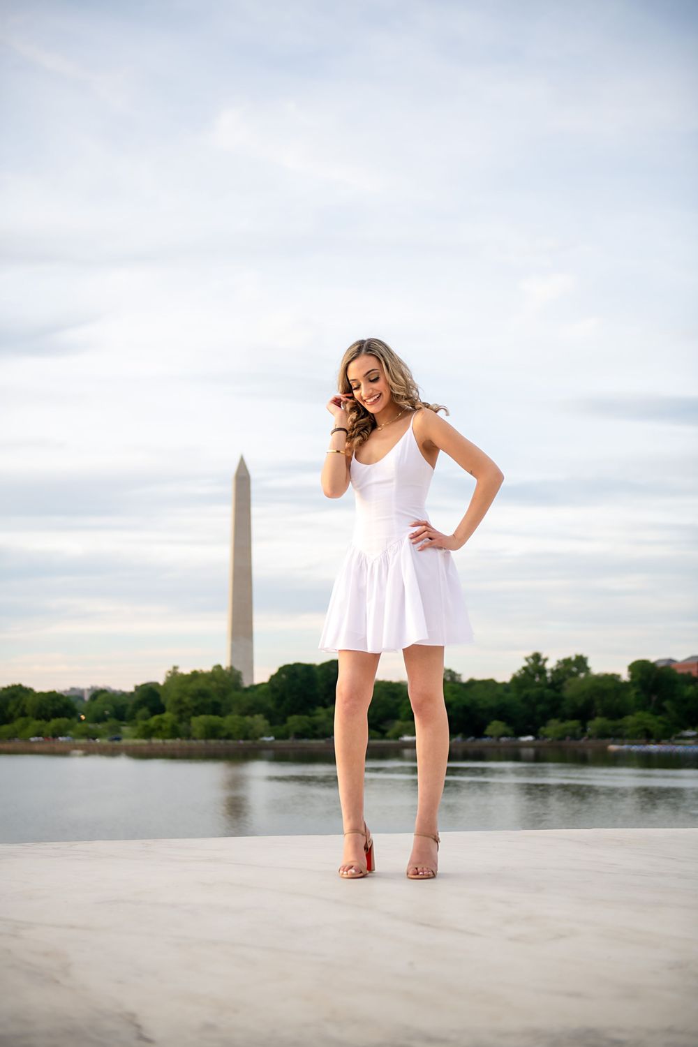 Dancing poses on marble steps with Washington Monument visible across water.