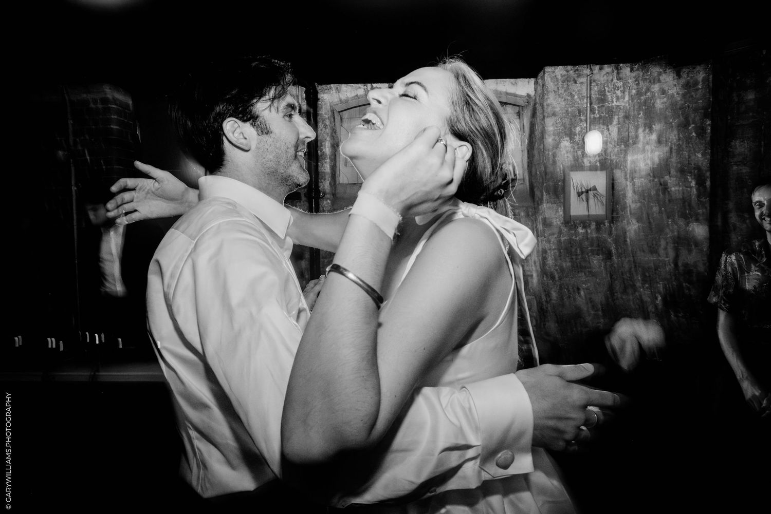 A black and white candid dance moment captured between a couple at a party.