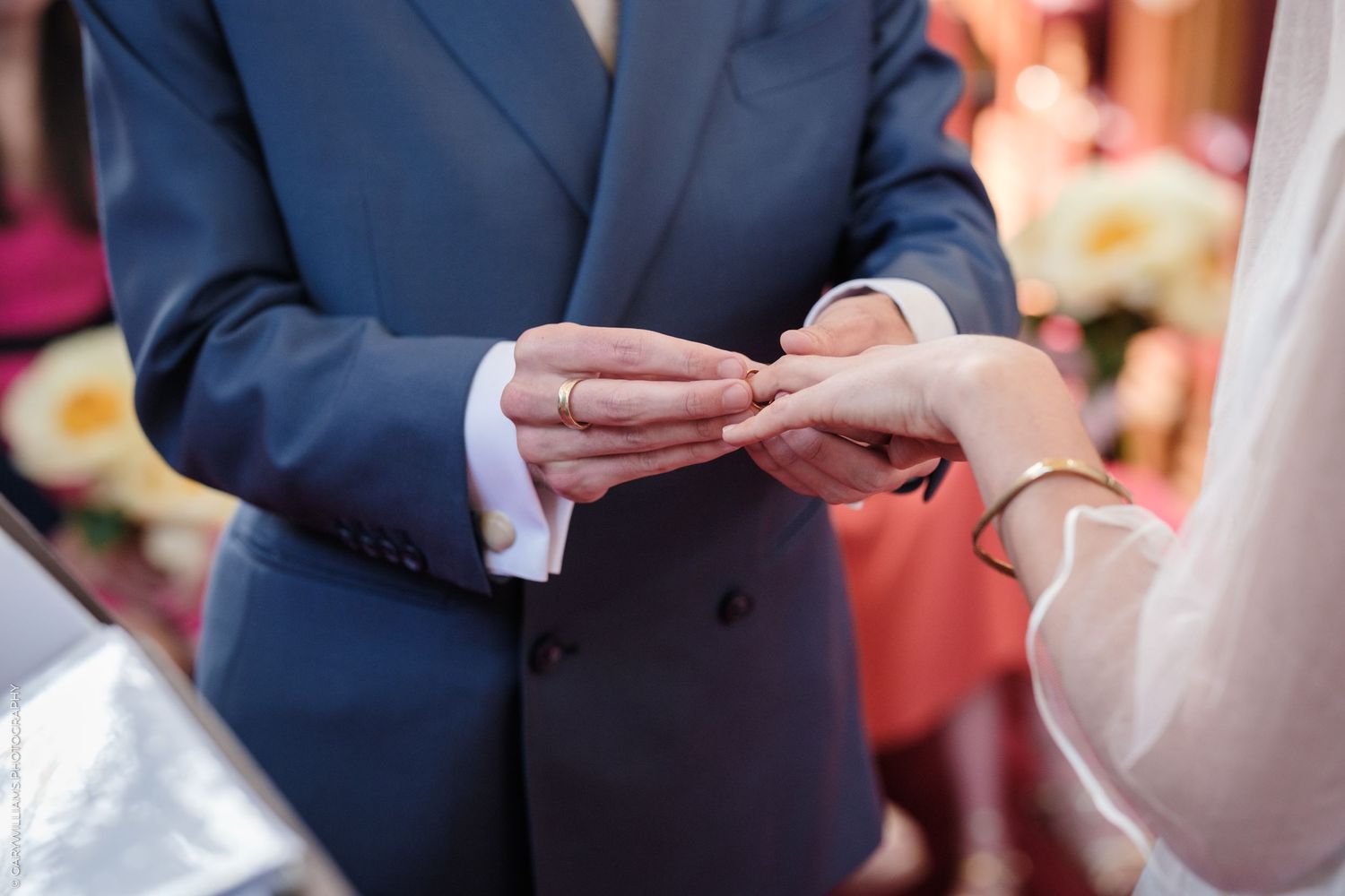 Close-up of hands during wedding ceremony as couple exchanges rings during traditional wedding ceremony.