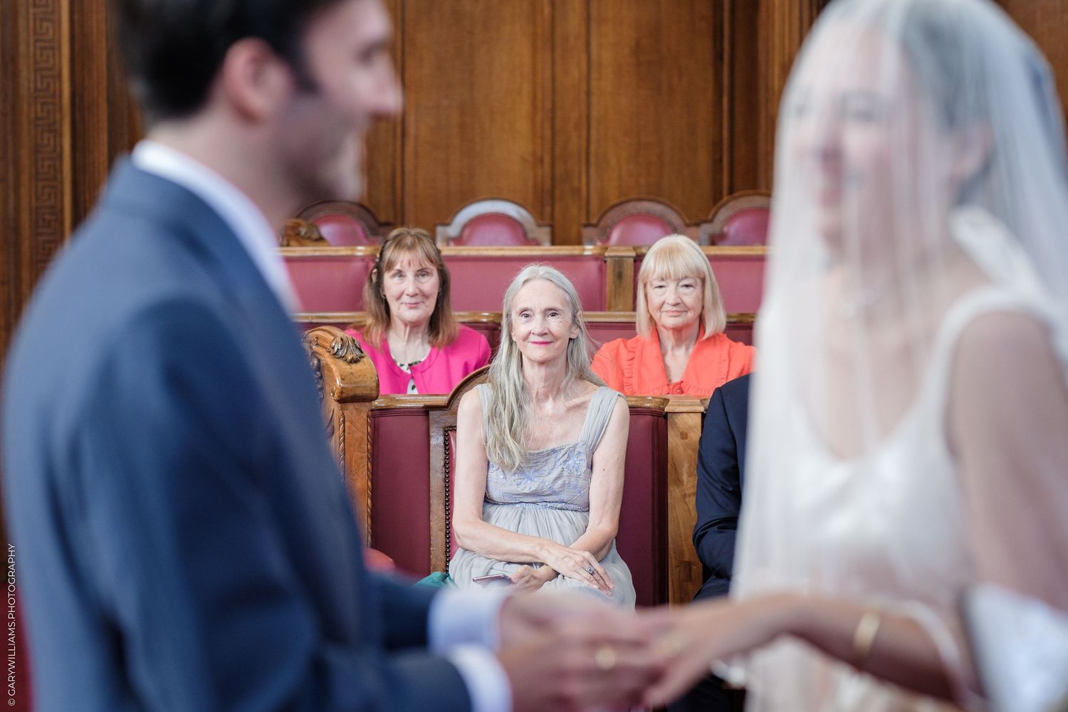 Guests watch attentively from wooden church pews during an indoor wedding ceremony.