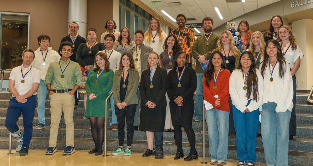Large group of diverse students and faculty members gather together for a group photo in an educational setting.