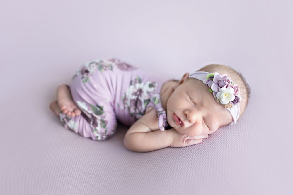 Sleeping newborn in floral outfit on lavender background. Photos by Tampa Photographer DigitalMyst Photography