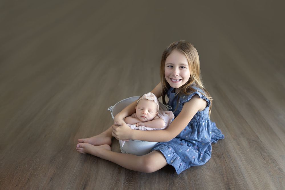 Sweet sibling moment captured on wooden floor in studio setting.