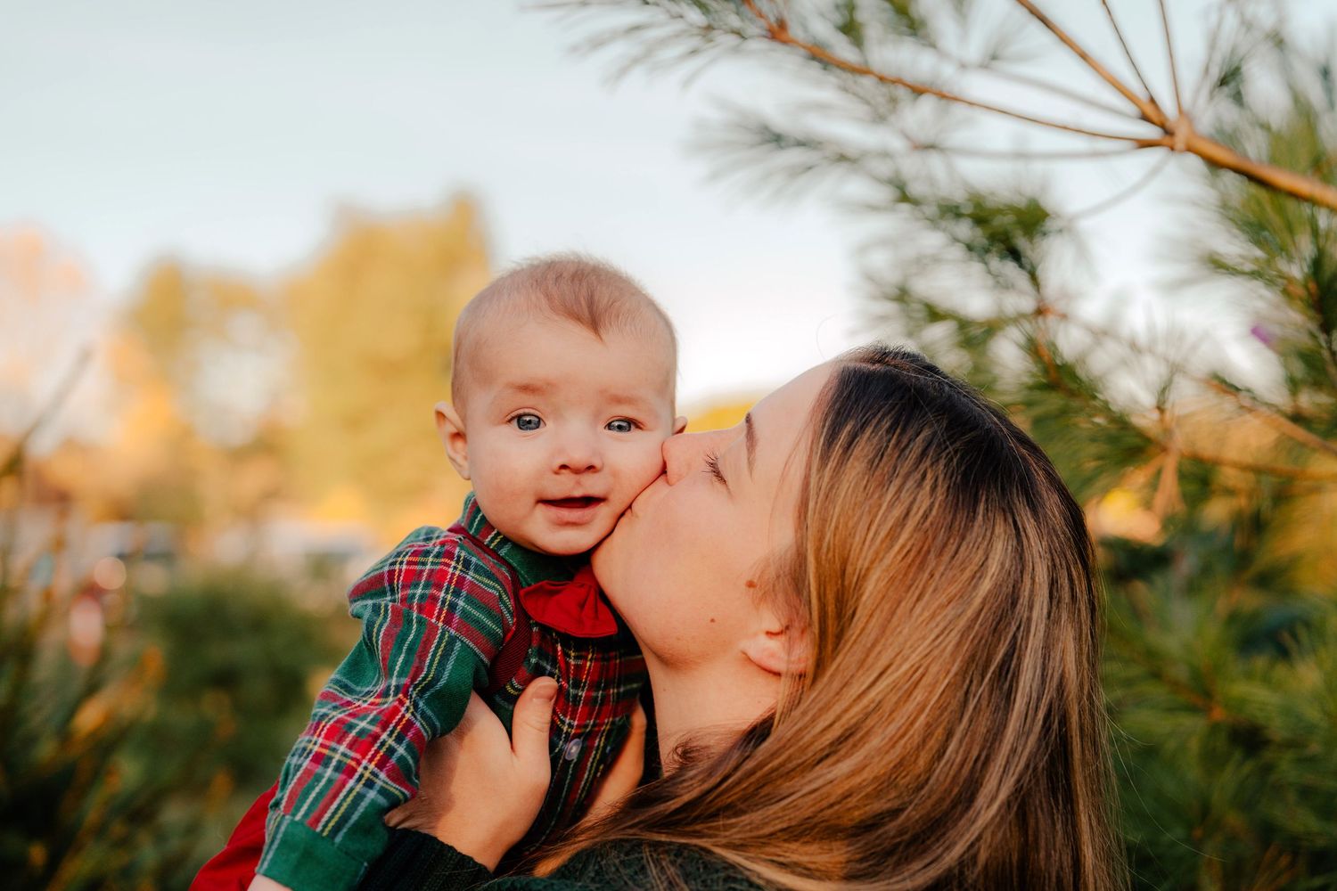 A tender moment between a parent and child wearing a plaid shirt outdoors during golden hour.