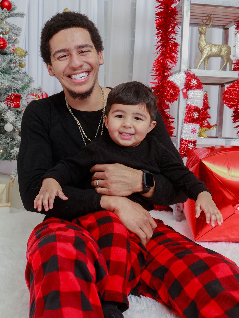 A cheerful Christmas photo with matching black tops and red plaid pajama pants.