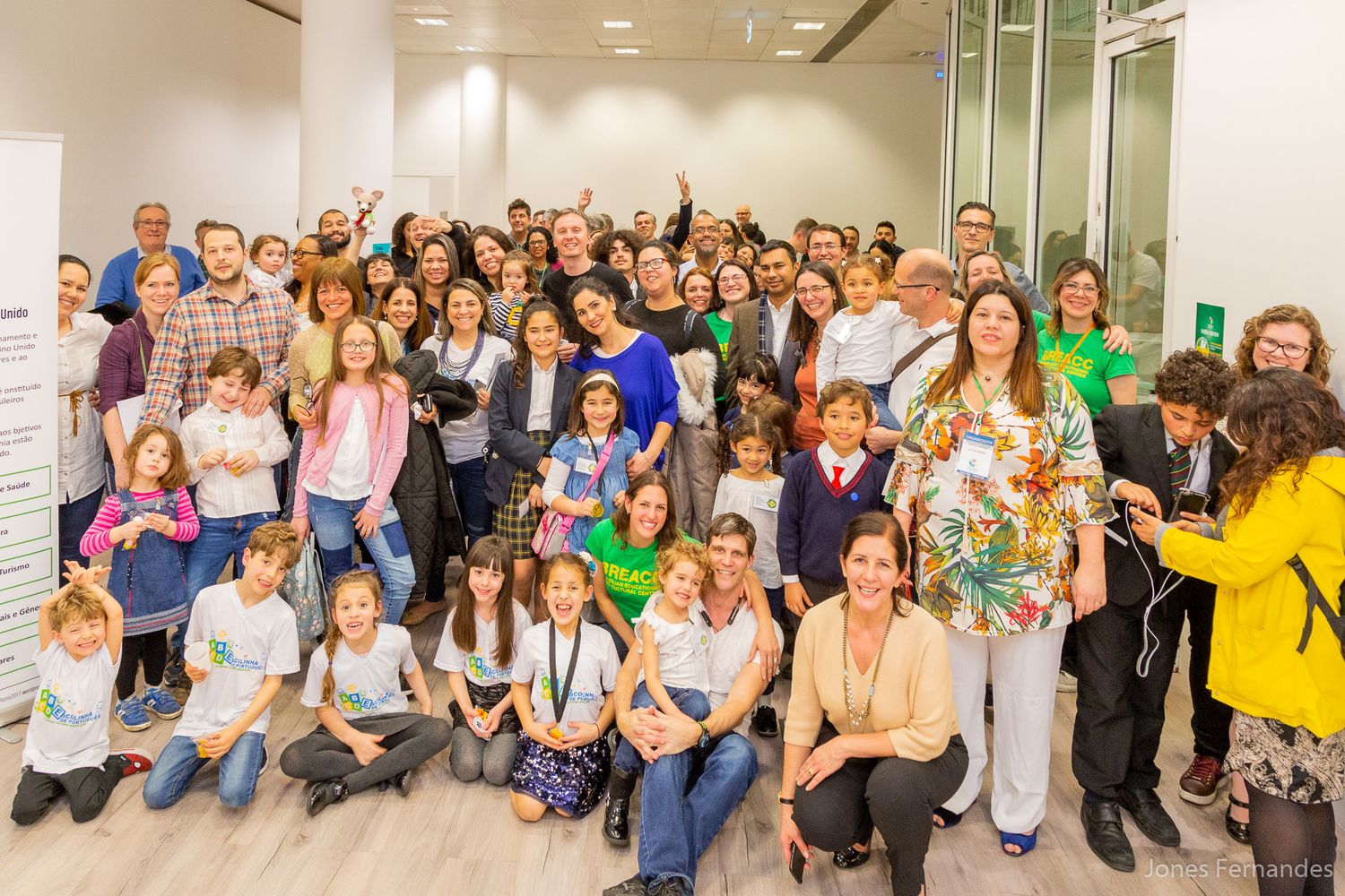 A large group of enthusiastic participants gather together for a group photo in a bright indoor space.