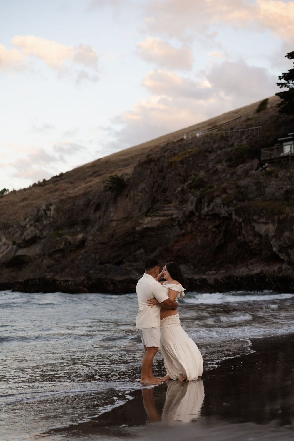 Couple cuddling together on the beach during maternity session at Taylor's Mistake Christchurch