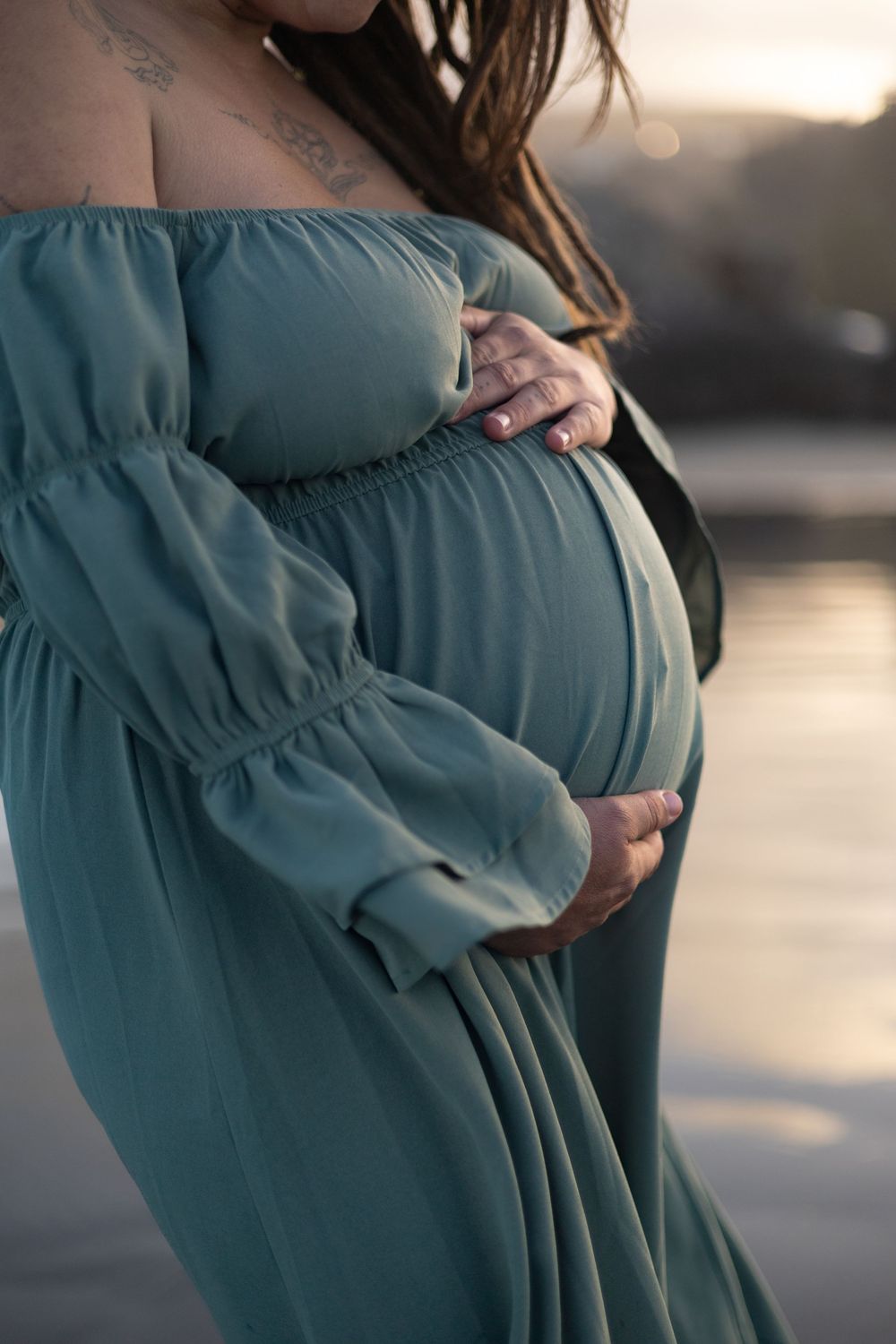 Close up of mums bump during beach maternity session at sunset