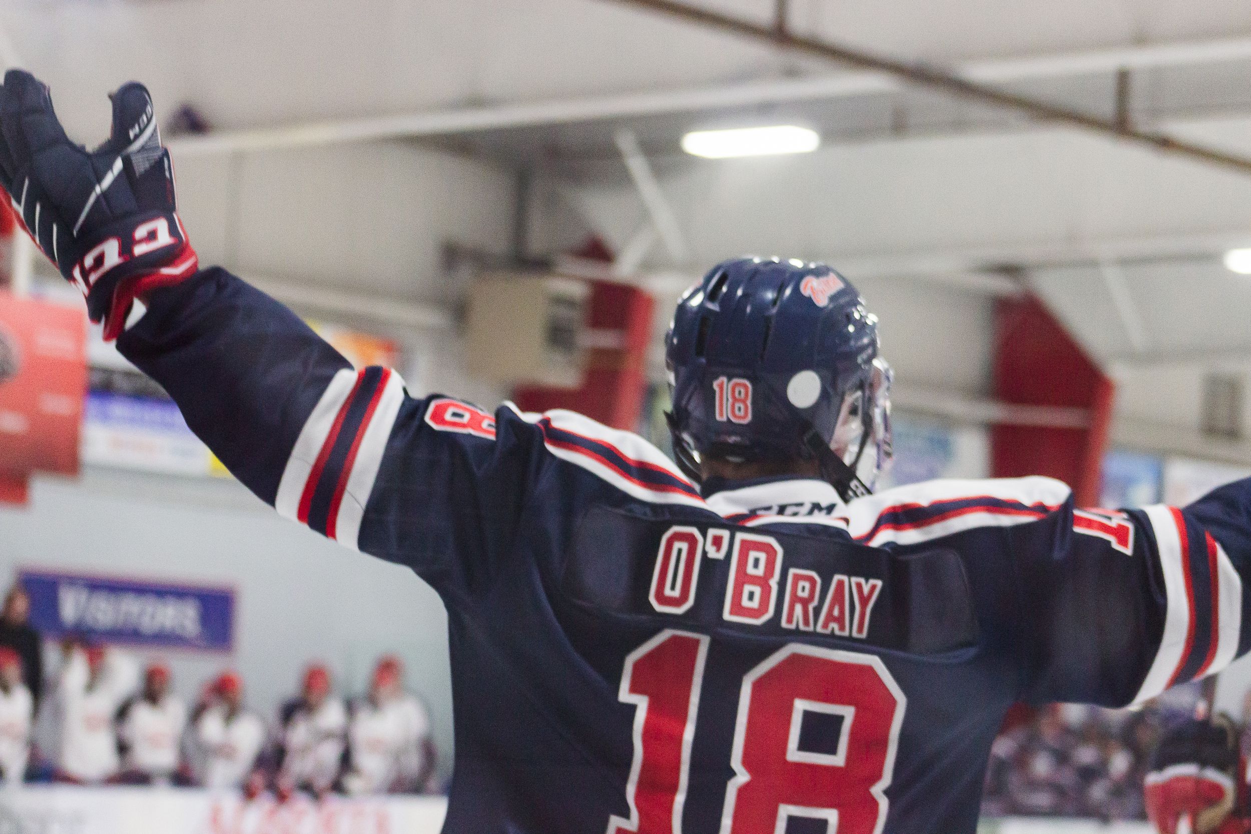 A hockey player in blue, number 18, celebrates. Jersey says O'Bray.