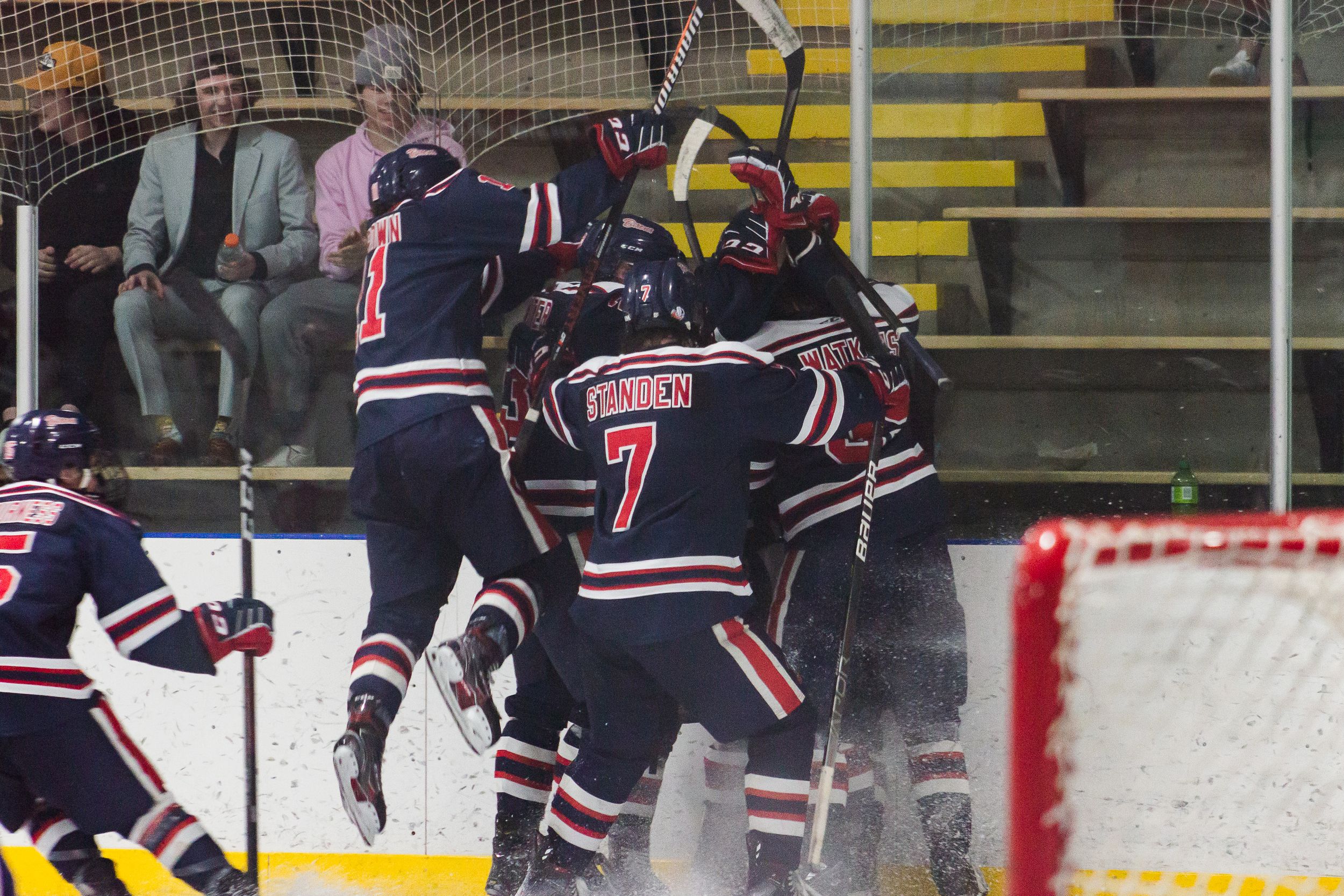 Hockey players celebrate jumping onto each other.