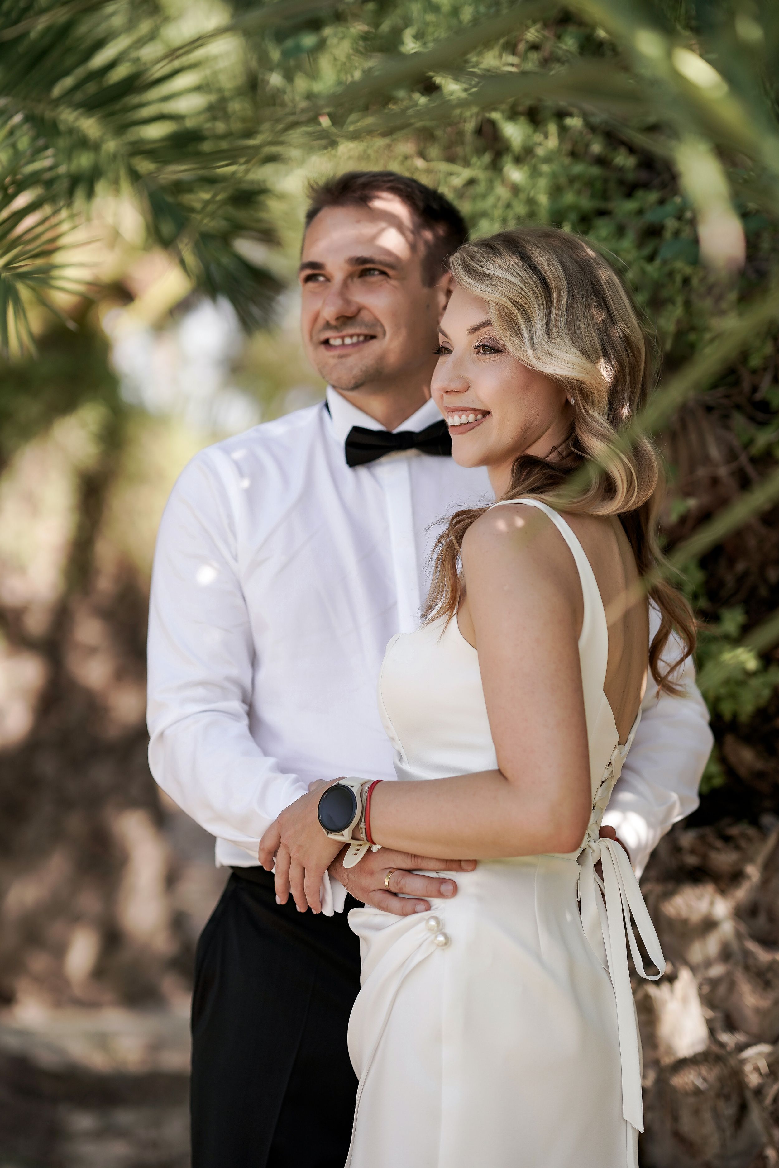 Newlyweds share intimate moments and laughter while posing in a lush garden setting.